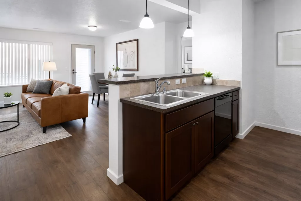 Modern open-plan living area with a kitchen island, brown sofa, dining table, and stylish decor in neutral tones.